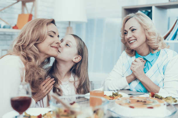 Family Celebrating Mother's Birthday at Home. Cake on Table. Happy Family. Mother with Daughter. Smiling Women. Smiling Grandmother. Celebration Concept. Glass of Wine. Hugging Together. - 写真・画像