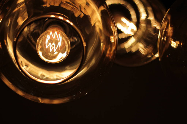 classic edison bulb in a transparent glass ceiling on a black background - Foto, immagini