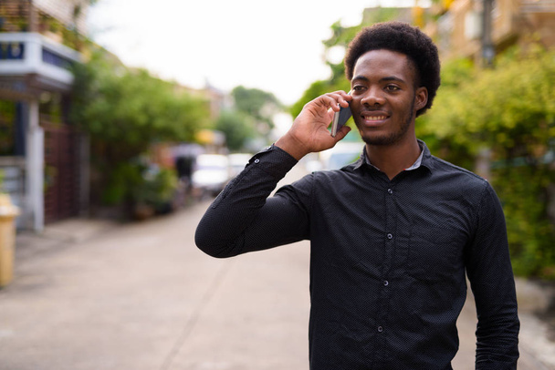 Fiatal csinos afrikai férfi szabadban mobiltelefon használata - Fotó, kép