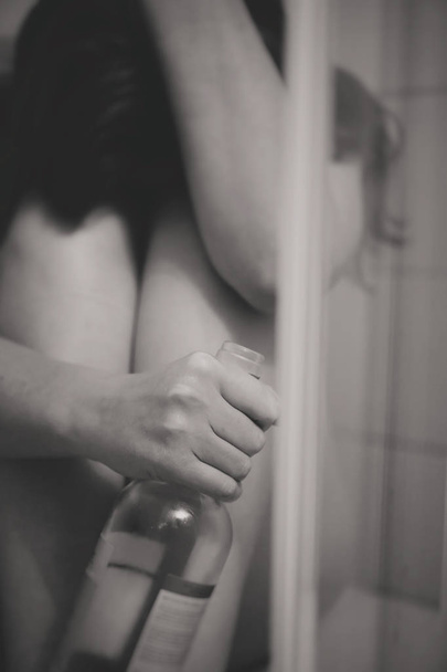 Καταθλιπτική γυναίκα με μπουκάλι κρασί στο ντους. - Φωτογραφία, εικόνα