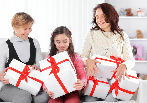 grandmother, mother and daughter with gift boxes sitting on the couch.holiday concept - 写真・画像
