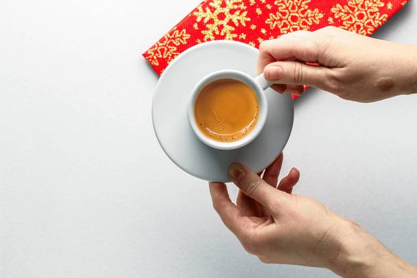 gemütliche, helle Weihnachtsfeier Konzept. Kaffeetasse in weiblichen Händen, helle Weihnachts-Serviette auf weißem Hintergrund. Ansicht von oben. flach lag. Kopierraum - Foto, Bild