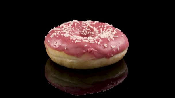 spinning donut with pink icing on a black background - Footage, Video