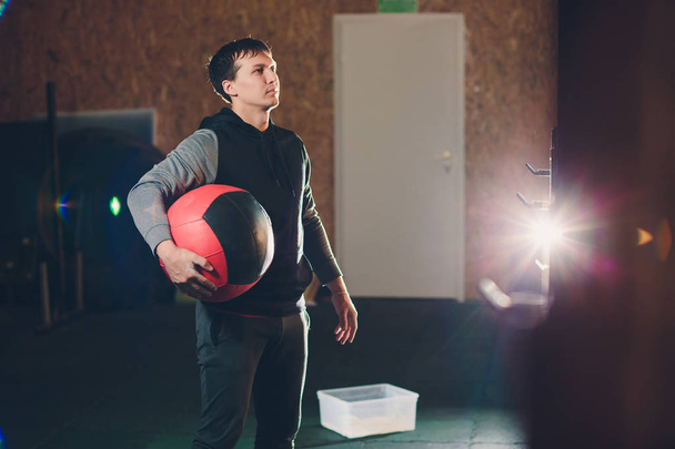 Атлетик делает упражнения на животе на полу. Человек делает тренировку с помощью мяча в тренажерном зале
. - Фото, изображение