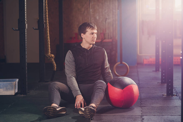 Athletic man doing abdomen exercise on the floor. Man doing workout using a medicine ball at the gym. - Fotografie, Obrázek