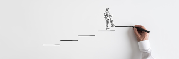 Image large de la main masculine dessinant homme d'affaires montant les escaliers vers le succès sur fond gris
. - Photo, image