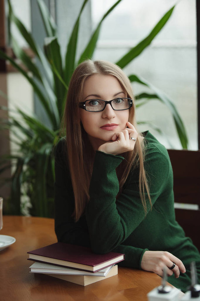Portrait of intelligent woman sitting with books in cafe - Zdjęcie, obraz
