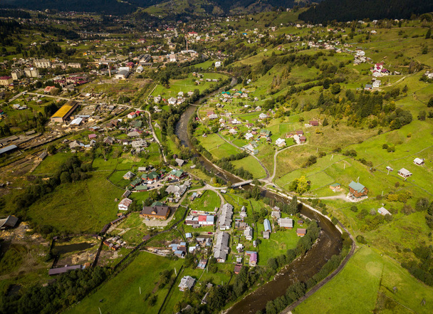 Beautiful aerial drone photo of small highland town in Carpathian mountains surrounded with forest and green hills.Popular travel destination for active tourism in Southern Europe. - Foto, Bild