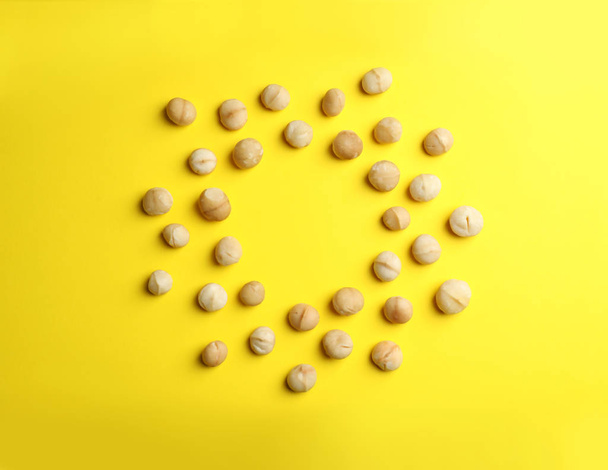 Marco hecho de nueces de macadamia orgánicas sin cáscara sobre fondo de color, vista superior. Espacio para texto
 - Foto, Imagen