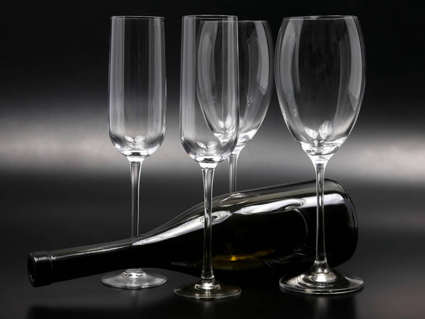 τέσσερις άδειο γυαλιά κρασιού και ένα ανακλινόμενο μπουκάλι κρασί - Φωτογραφία, εικόνα