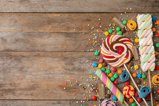 Flat lay composition with different yummy candies and space for text on wooden background - Foto, immagini