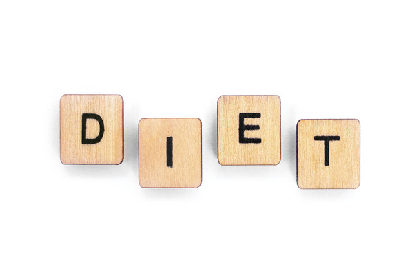 The word DIET - spelt with wooden letter tiles over a white background. - Foto, afbeelding