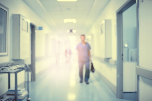 Hospital hallway with the silhouette of a medical doctor in the rays of a mysterious light, defocused backgroun - Photo, Image