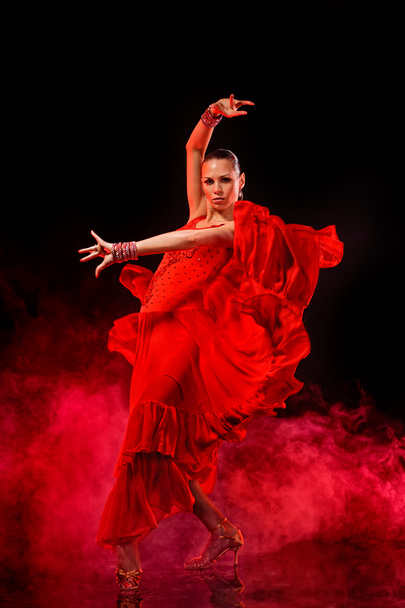 Young woman dancing Latino on dark smoky background - Foto, afbeelding