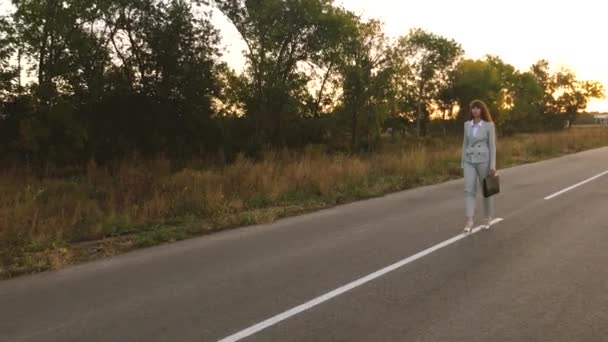 business woman with black briefcase walks on the asphalt with white markings - Záběry, video