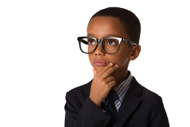 Κομψό μικρό στοχαστικό Αφρικανικός-αμερικανική αγόρι με τα γυαλιά στο επαγγελματικό κοστούμι. Studio που γυρίστηκε. Νεαρό αγόρι ποζάρει. Copyspace - Φωτογραφία, εικόνα