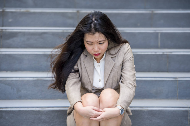 young depressed and desperate Asian Chinese businesswoman crying alone sitting on street staircase suffering stress and depression crisis being victim of mobbing or fired losing her job - Φωτογραφία, εικόνα