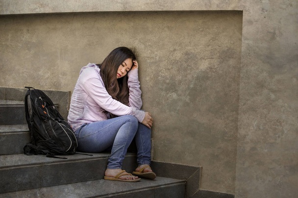 young sad and depressed Asian Korean student woman or bullied teenager sitting outdoors on street staircase overwhelmed and anxious feeling desperate suffering depression problem  - Foto, afbeelding