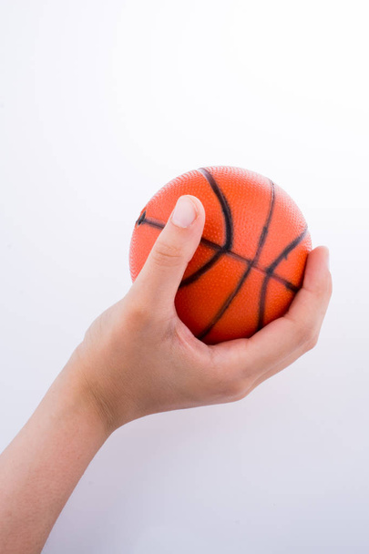 Hand holding an orange basketball model on a white background - Foto, afbeelding