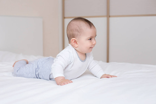 a portrait of a Little cute baby is crawling on a white bed - Φωτογραφία, εικόνα