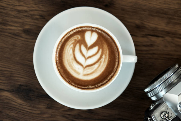 Xícara de café quente latte no fundo da mesa de madeira com luz solar quente da manhã. conceito fim de semana feliz
. - Foto, Imagem