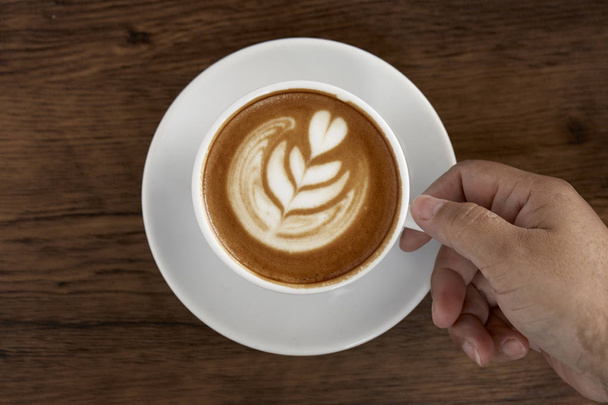Κύπελλο latte ζεστός καφές σε φόντο τραπέζι από ξύλο με ζεστές πρωί φως του ήλιου. Happy Σαββατοκύριακο έννοια. - Φωτογραφία, εικόνα