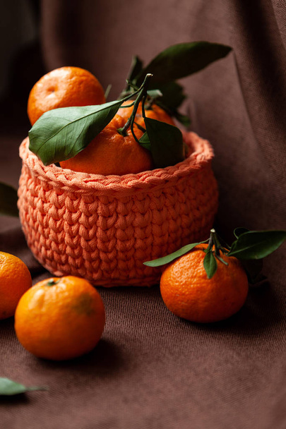 Orange knitted baskets with tangerines on brown background - Φωτογραφία, εικόνα