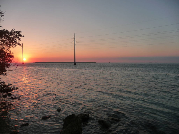 tengeri táj, elektromos vezetékek, naplementekor - Fotó, kép