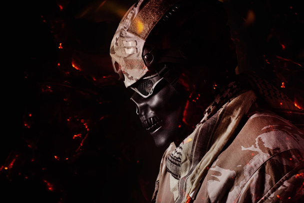 Military skeleton soldier in camouflage outfit profile view with fire ashes flying standing on black background. - 写真・画像