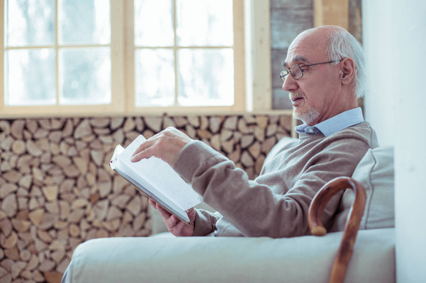 Concentrated mature man reading book at home - Valokuva, kuva