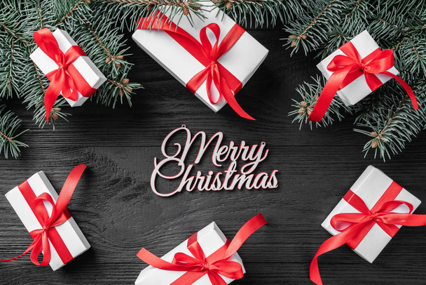白い贈り物や暗いの木製の素朴な背景、テキスト上のモミの枝とクリスマス カード。クリスマスと幸せな新年のグリーティング カード。平面図、平面レイアウト.  - 写真・画像