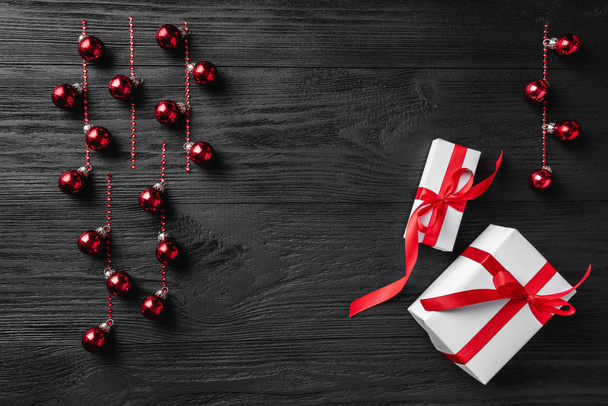 Cadeaux de Noël blancs avec des boules de Noël sur un fond en bois sombre, emplacement plat. Espace de copie. Vue d'en haut. Noël et bonne année carte de voeux
. - Photo, image