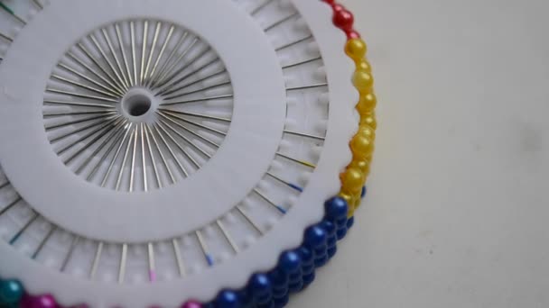 A seamstress woman removes a pin with plastic head from a set of white discs. Dressmaker get a multi-colored needle and put it back - Footage, Video