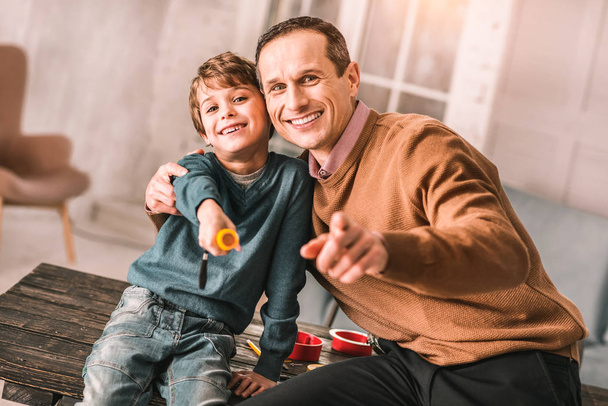 Handsome adult man smiling sincerely while posing with his little boy. - Foto, Bild