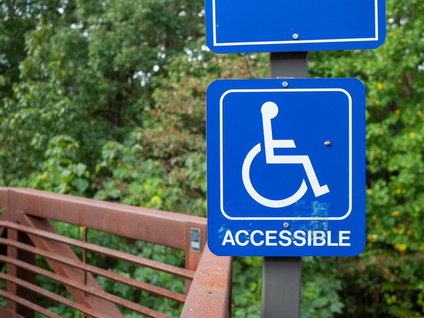 Blue accessible handicap sign hanging on nature hiking path - Photo, Image