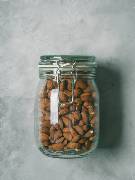 Fresh almond in glass jar on concrete background - Fotó, kép