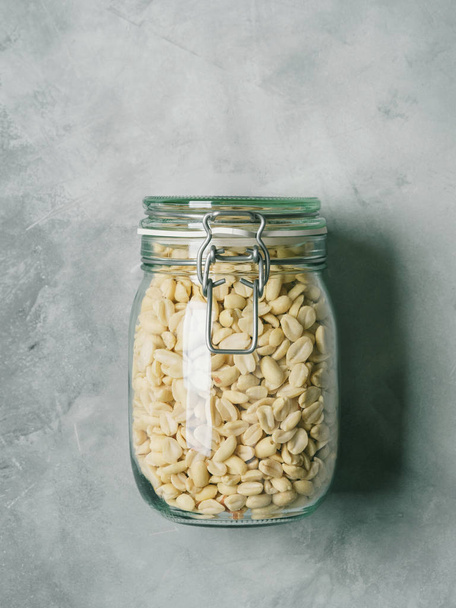 Fresh peanut in glass jar on concrete background - Fotó, kép