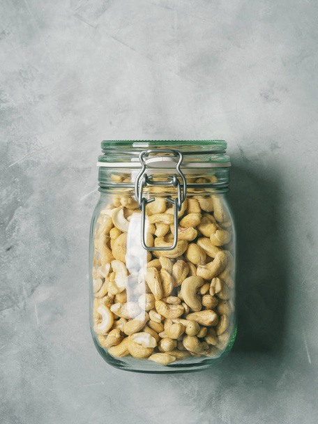 Fresh cashew nuts in glass jar on concrete background - Foto, Imagem