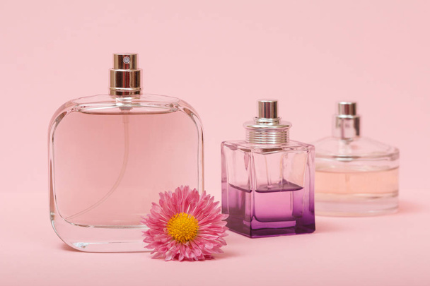 Bottles with women perfume and flower bud in a pink background. Women products. - Foto, Imagem