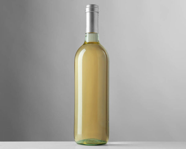 Μπουκάλι λευκό κρασί σε γκρίζο φόντο - Φωτογραφία, εικόνα