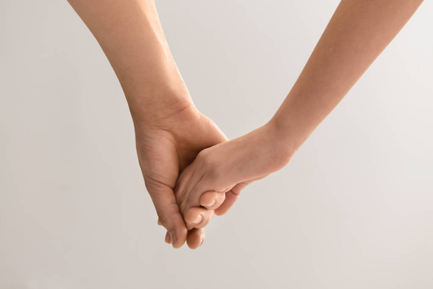 Mężczyzna i kobieta trzymając się za ręce na jasnym tle - Zdjęcie, obraz