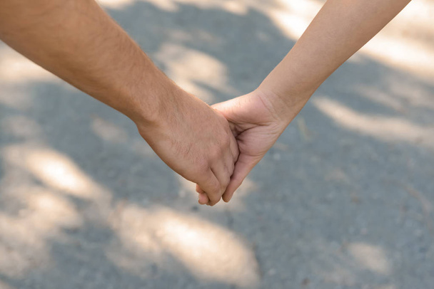man en vrouw hand in hand buitenshuis - Foto, afbeelding