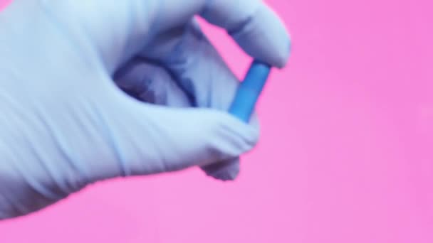 Una mano in un guanto medico blu tiene una capsula pillola blu
. - Filmati, video