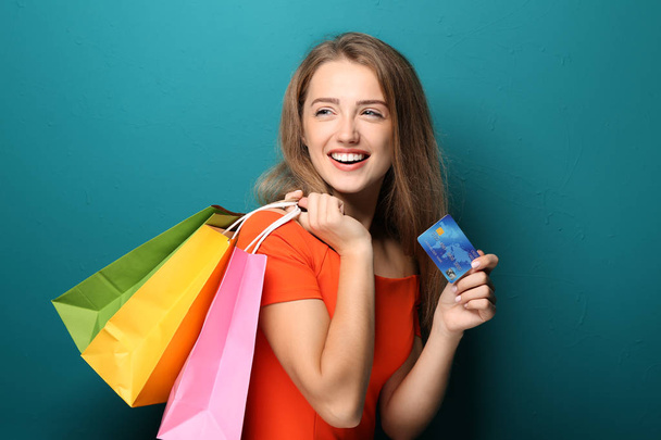Alışveriş torbaları ve renk arka plan üzerinde kredi kartı ile mutlu güzel kadın - Fotoğraf, Görsel