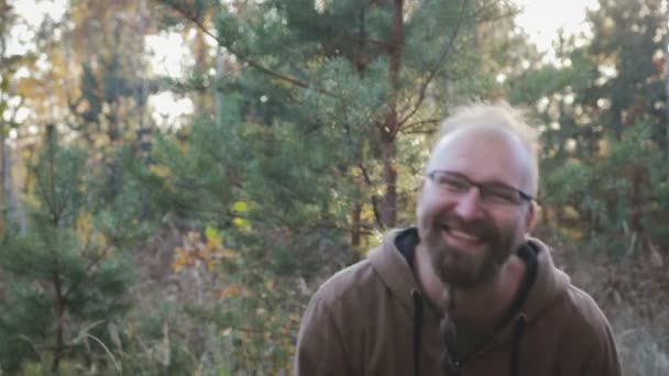 Portret van een vrolijke bebaarde man met bril op een bos achtergrond - Video