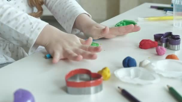 a little girl plays with plasticine, rolls balls, there are figures and colored pencils on the desktop, the development of fine motor skills of hands - Footage, Video
