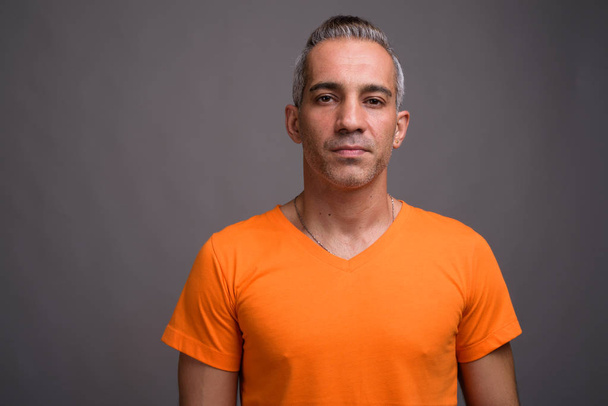 Hombre persa guapo con pelo gris vistiendo camiseta naranja
 - Foto, imagen