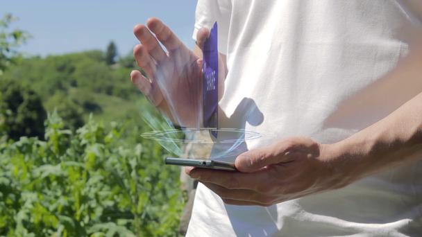 Mann zeigt Konzept-Hologramm-Aktie auf seinem Handy - Filmmaterial, Video