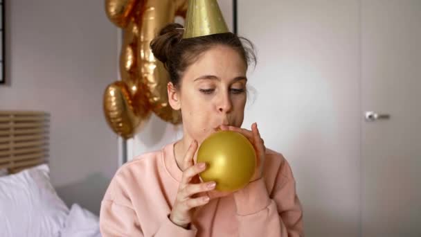 Urodziny dziewczyna dmuchanie złota balon - Materiał filmowy, wideo