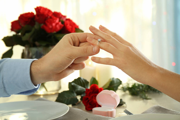 Junger Mann legt Verlobungsring bei romantischem Date an den Finger seiner Verlobten - Foto, Bild